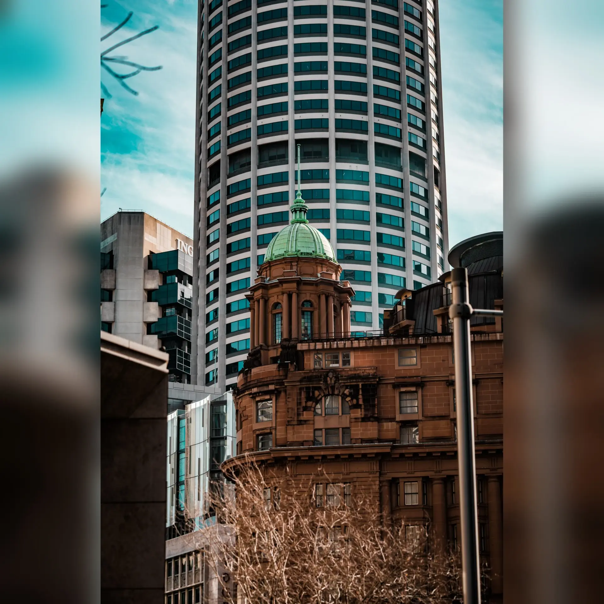 Historic sandstone building facade contrasted with a glass high-rise behind it